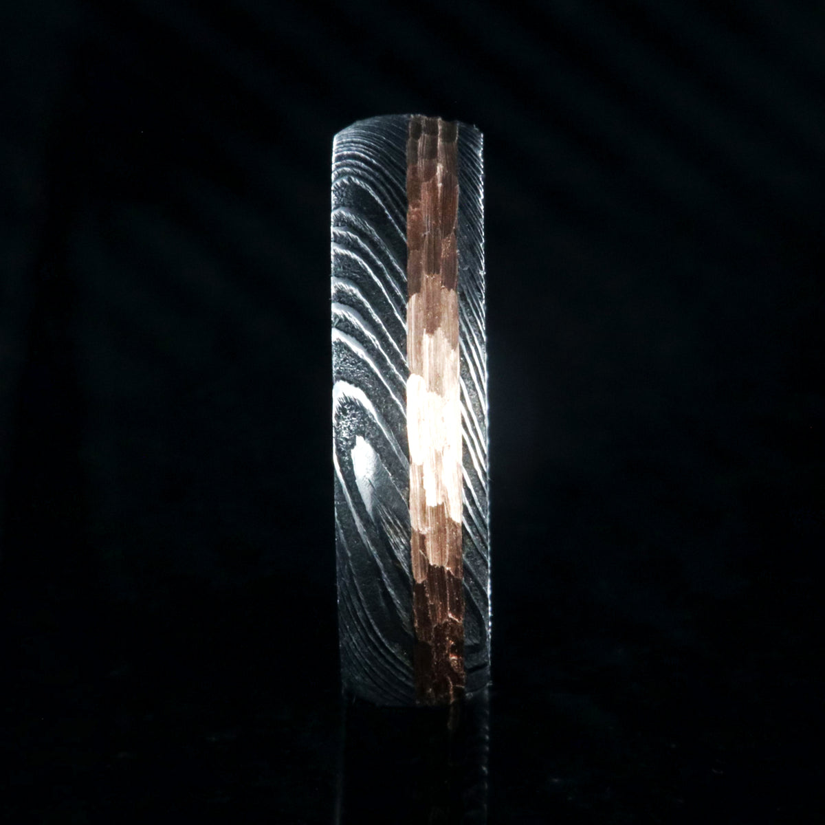 6mm wide black Damascus steel wedding band with a 2mm wide hammered rose gold inlay