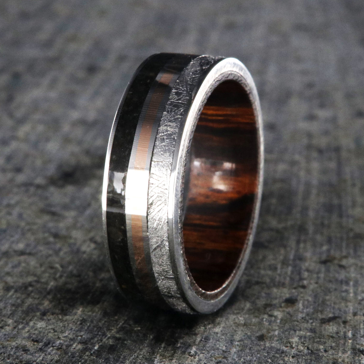 7mm wide wedding band with rose gold center inlay, Gibeon meteorite edge, dinosaur bone edge, and Arizona ironwood sleeve
