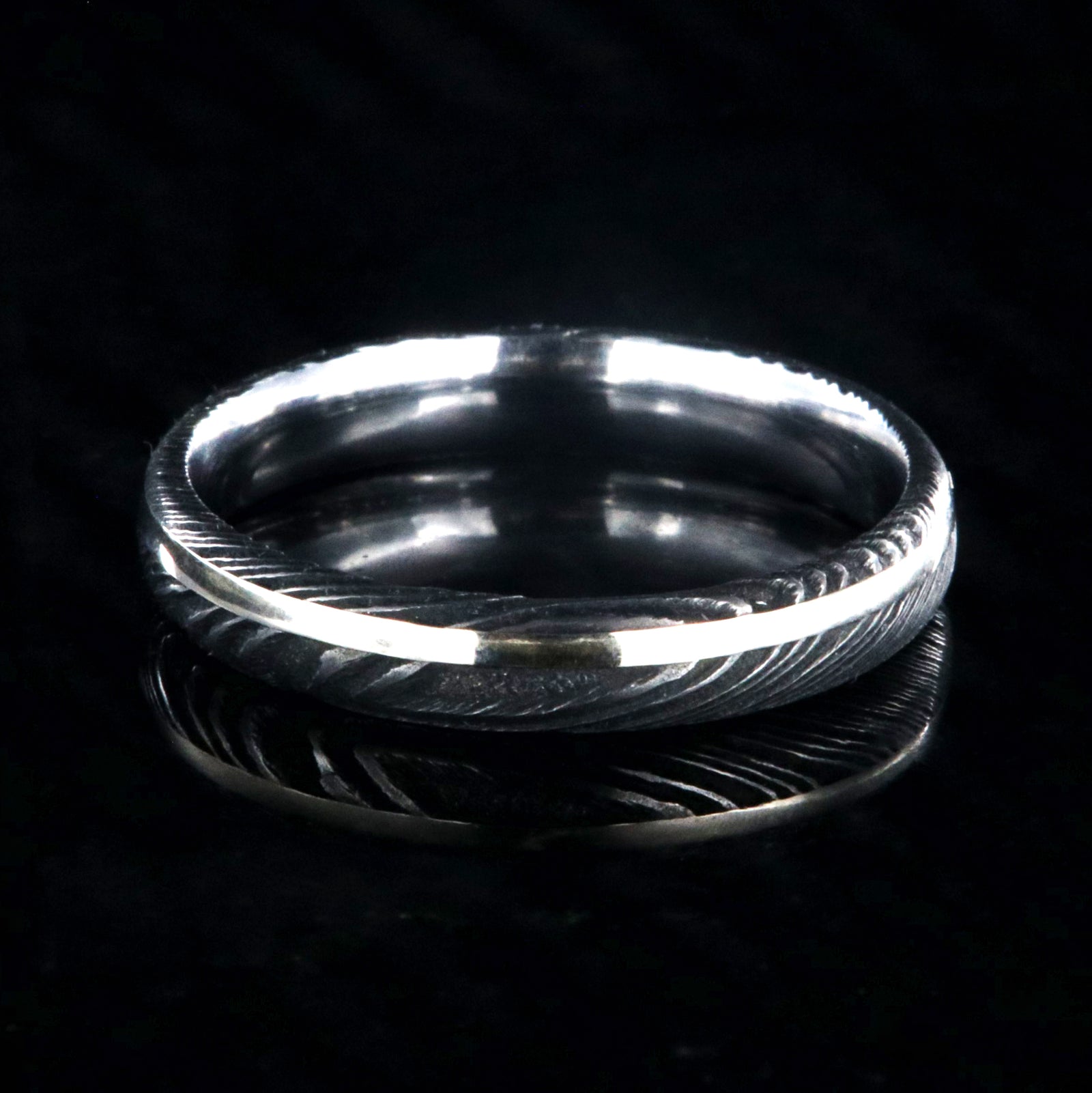 4mm wide black Damascus steel wedding band with a white gold inlay