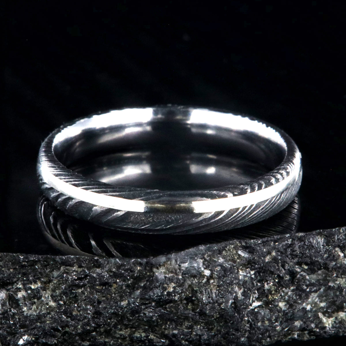 4mm wide black Damascus steel wedding band with a white gold inlay