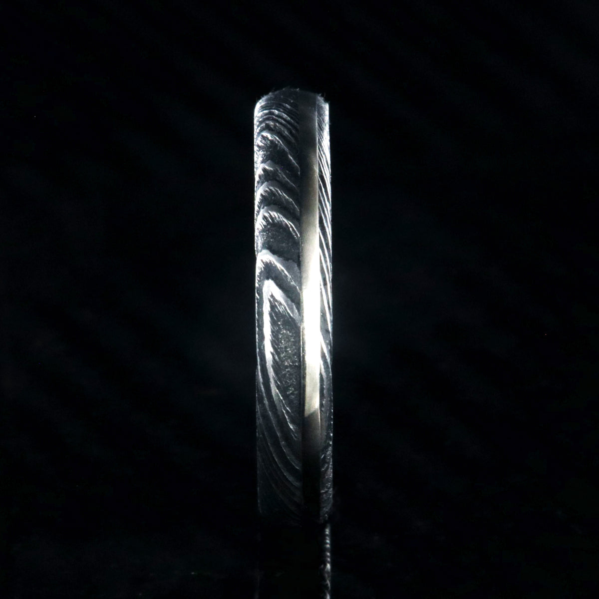 4mm wide black Damascus steel wedding band with a white gold inlay