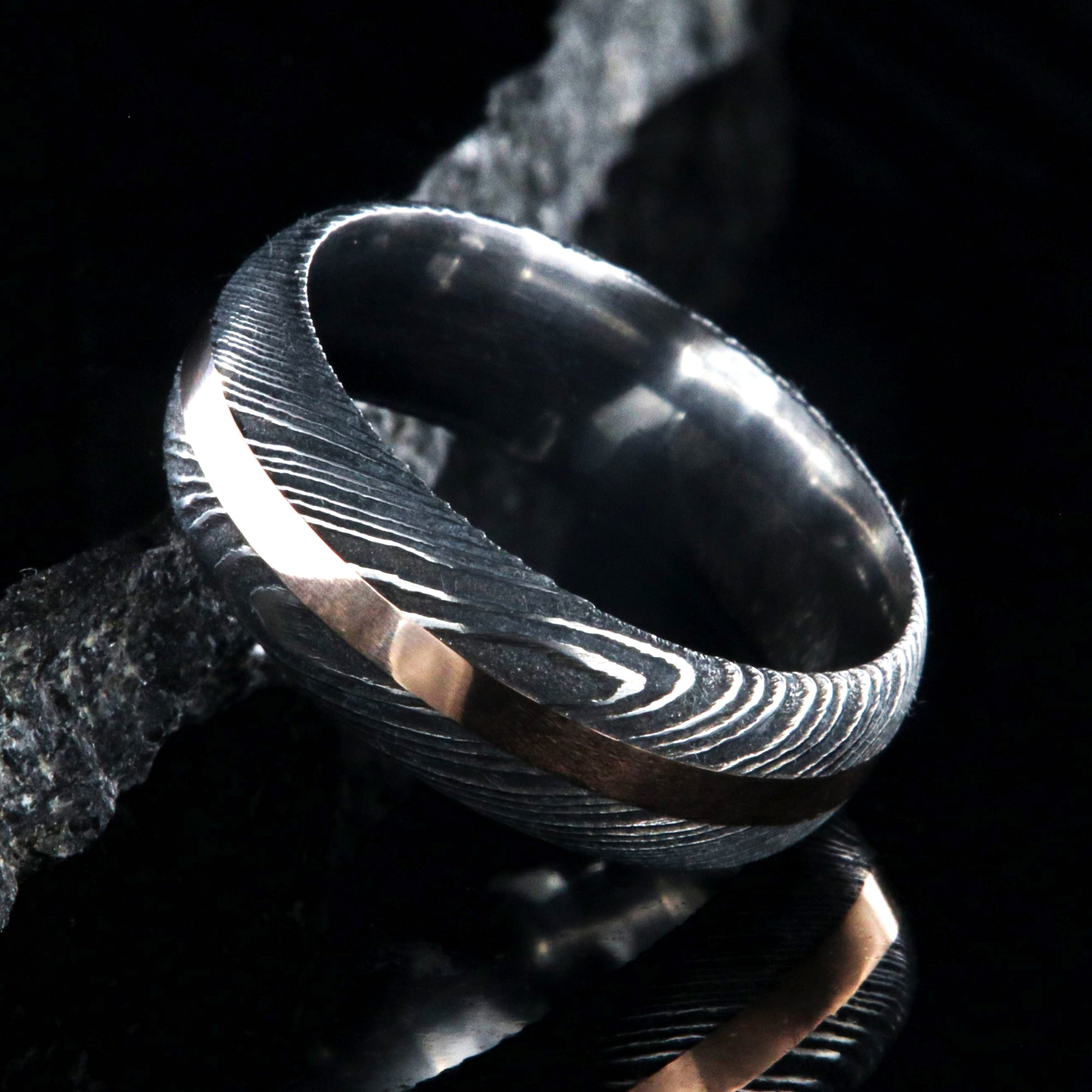 8mm wide black Damascus steel wedding band with a centered rose gold inlay and rounded profile