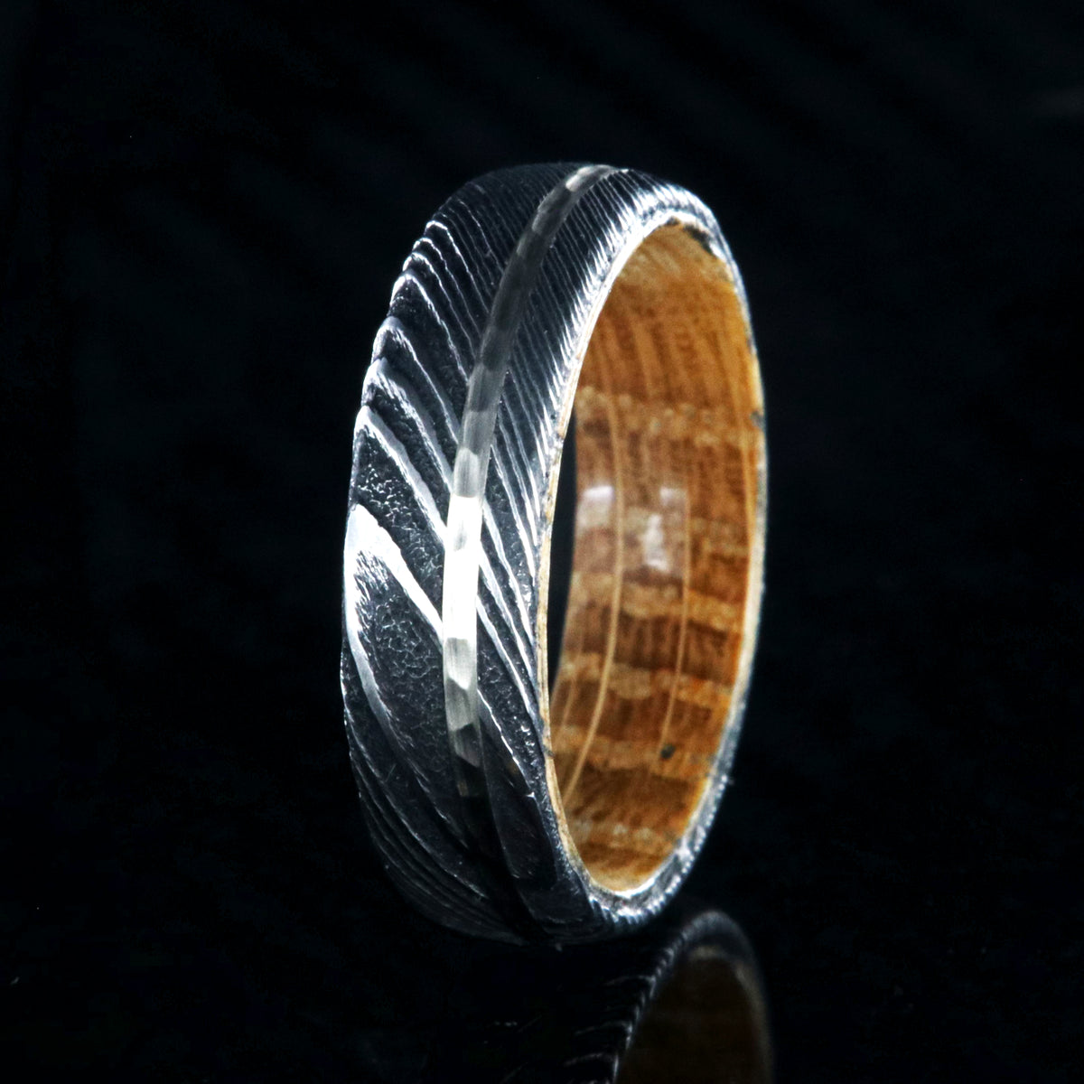 6mm wide black Damascus steel wedding band with a 1mm wide hammered white gold inlay
