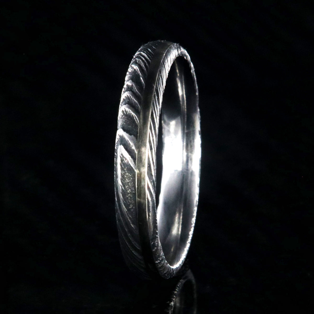 4mm wide black Damascus steel wedding band with a white gold inlay