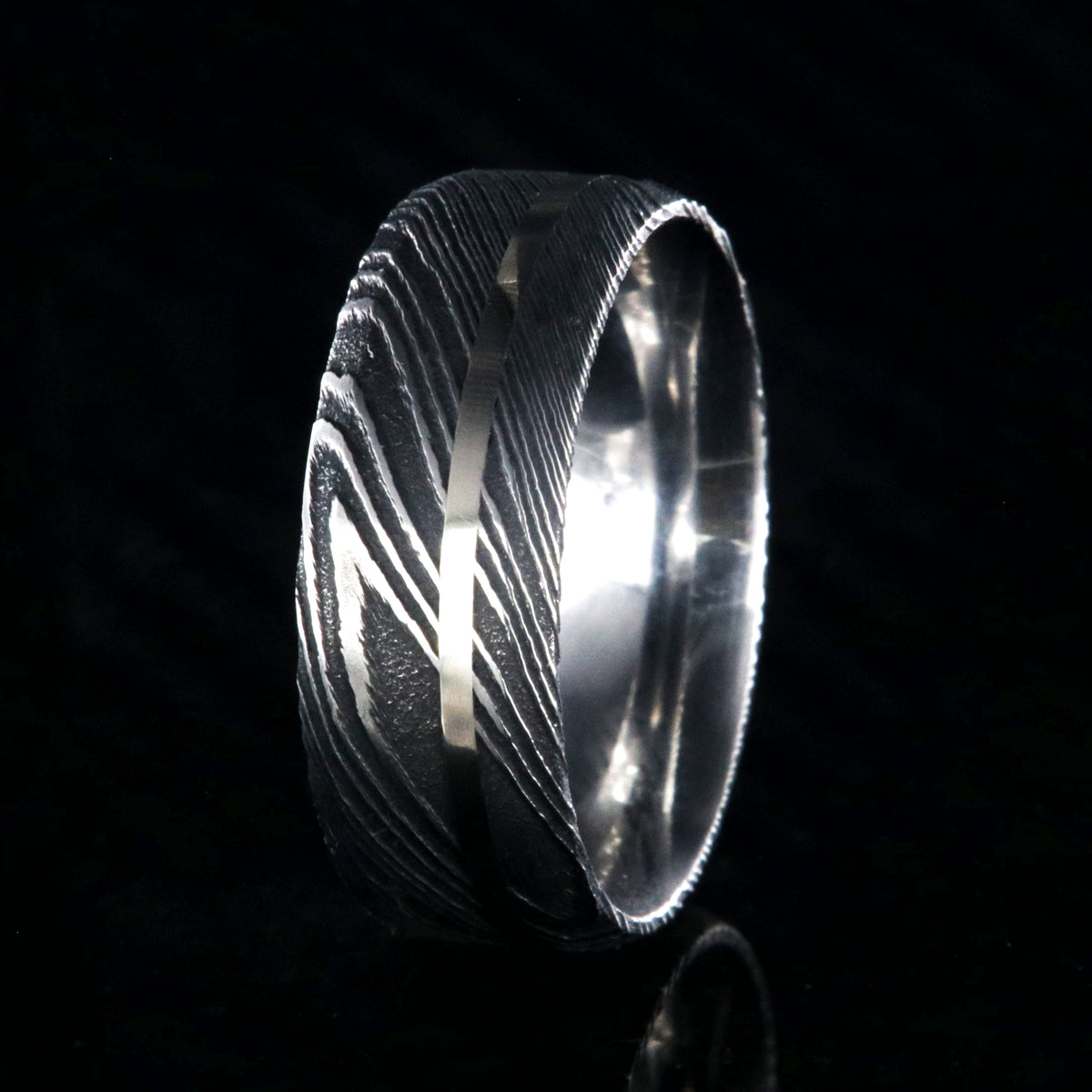 8mm wide black Damascus steel wedding band with a white gold inlay and flat profile