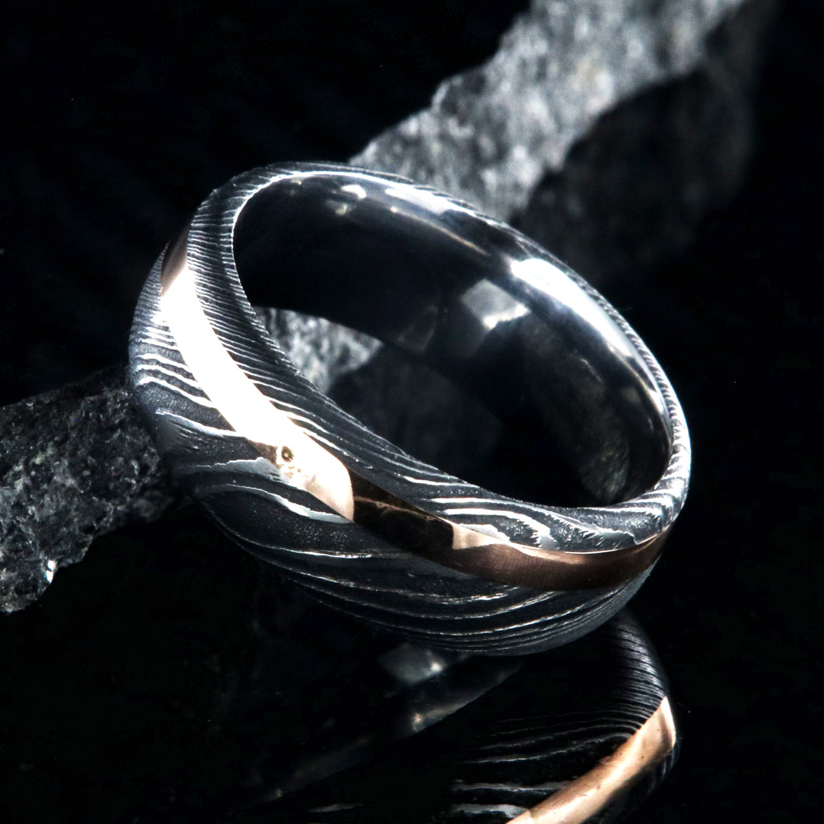 8mm wide black Damascus steel wedding band with a 2mm wide rose gold inlay and rounded profile