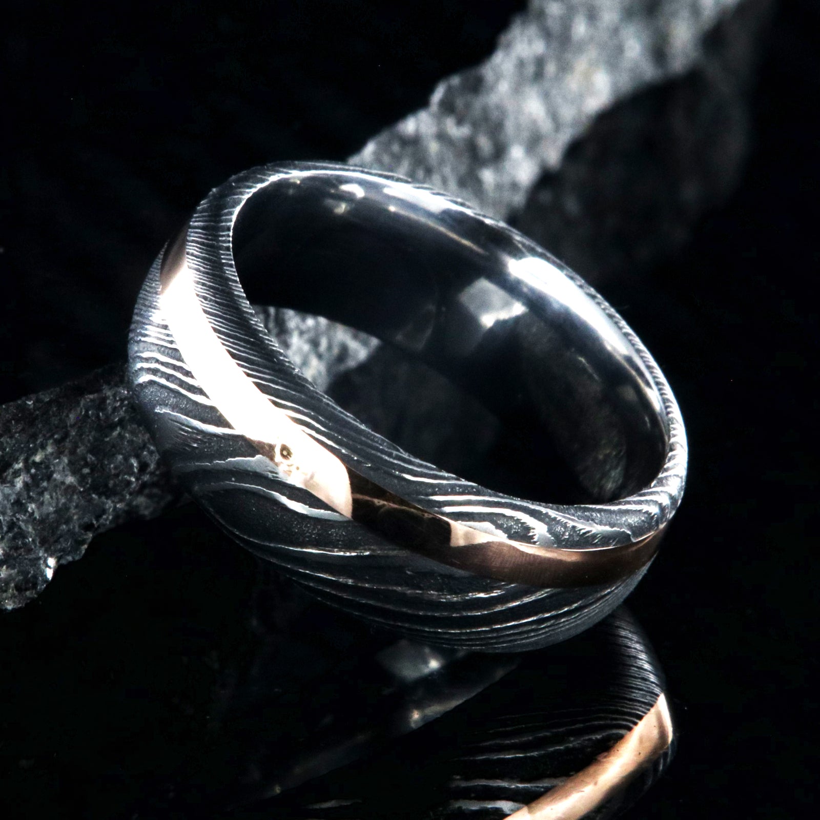 8mm wide black Damascus steel wedding band with a 2mm wide rose gold inlay and rounded profile