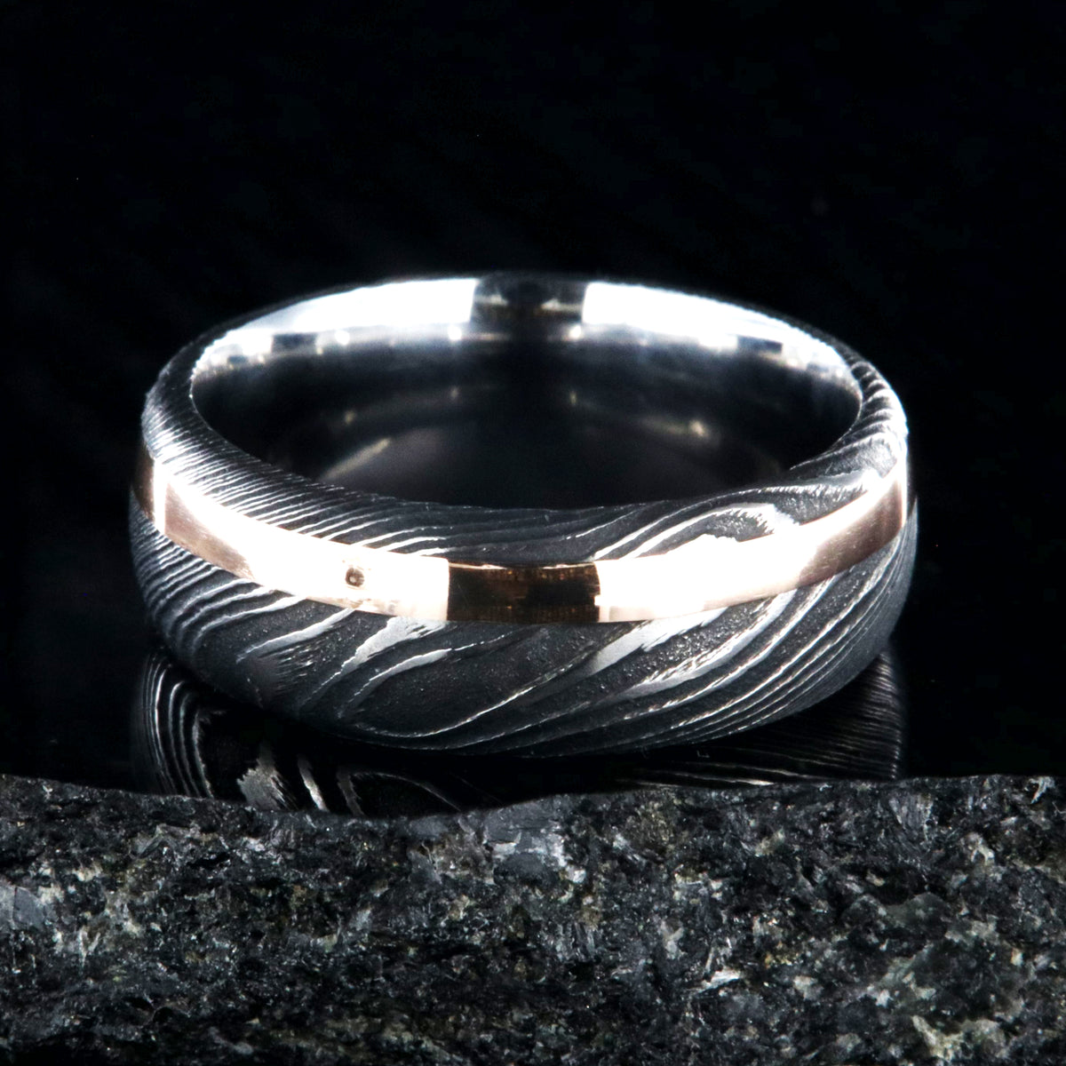 8mm wide black Damascus steel wedding band with a 2mm wide rose gold inlay and rounded profile