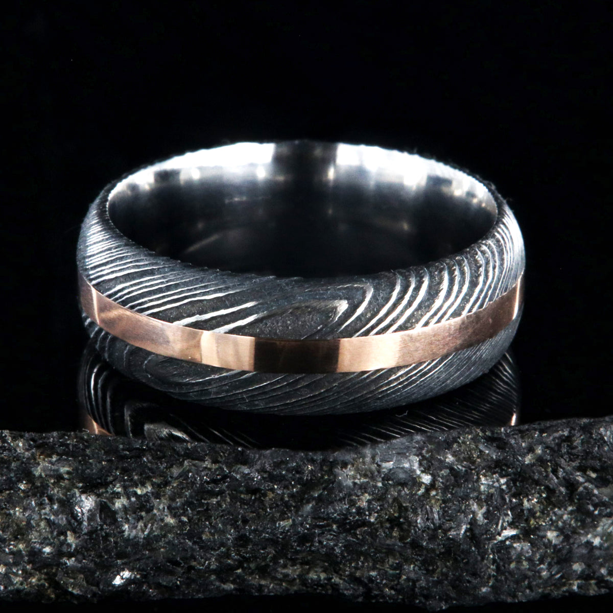 8mm wide black Damascus steel wedding band with a centered rose gold inlay and rounded profile