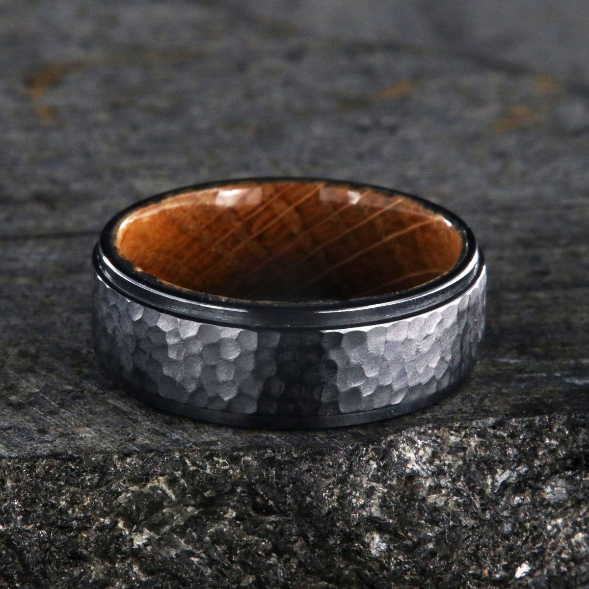 8mm wide black titanium wedding band with a raised center and hammered finish with a whiskey barrel sleeve