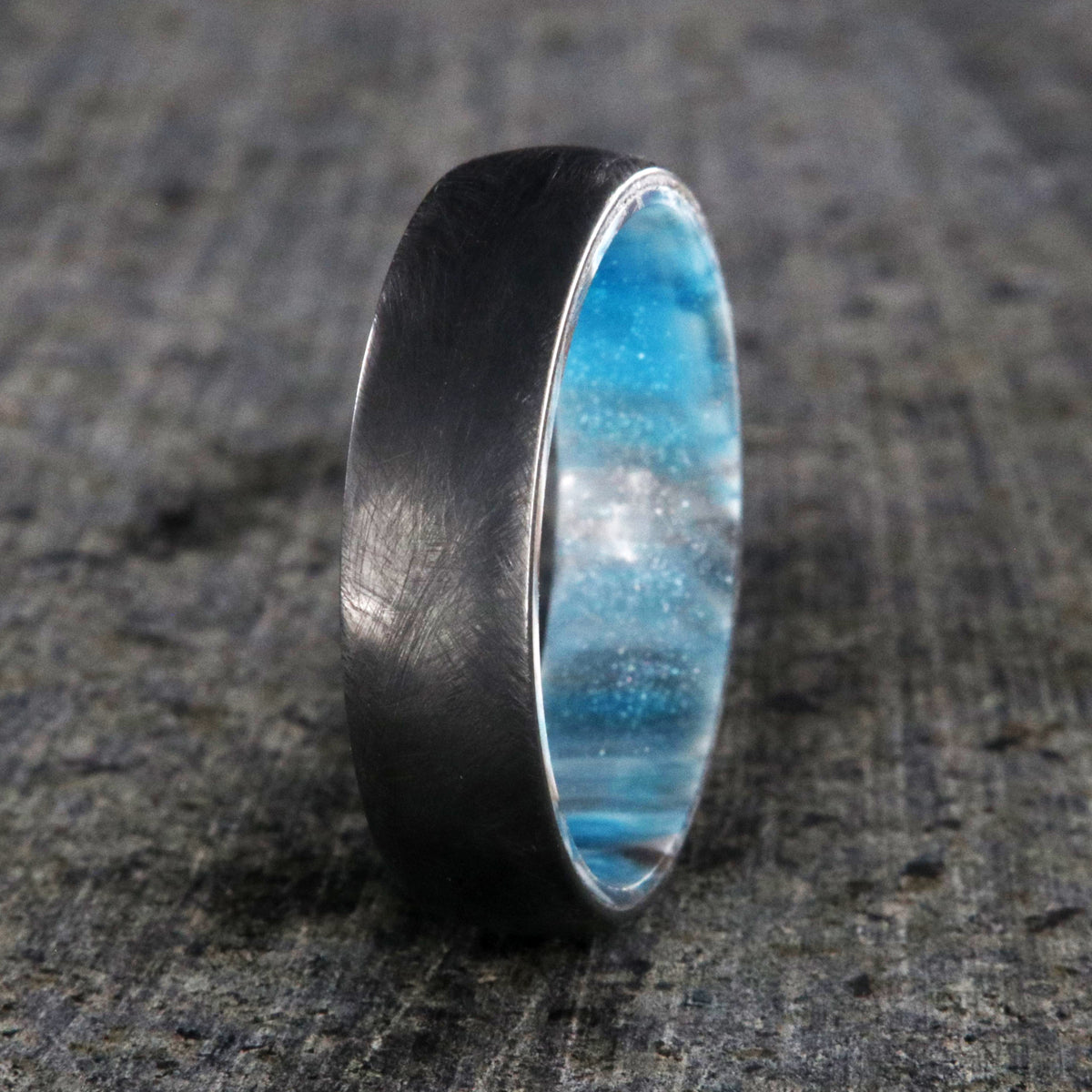 6mm wide black zirconium wedding band with a distressed finish and a blue, white, and brown DiamondCast sleeve