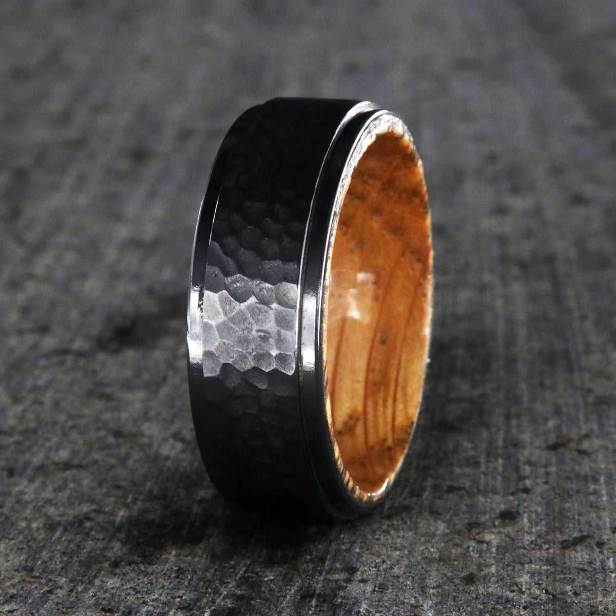 8mm wide black titanium wedding band with a raised center and hammered finish with a whiskey barrel sleeve