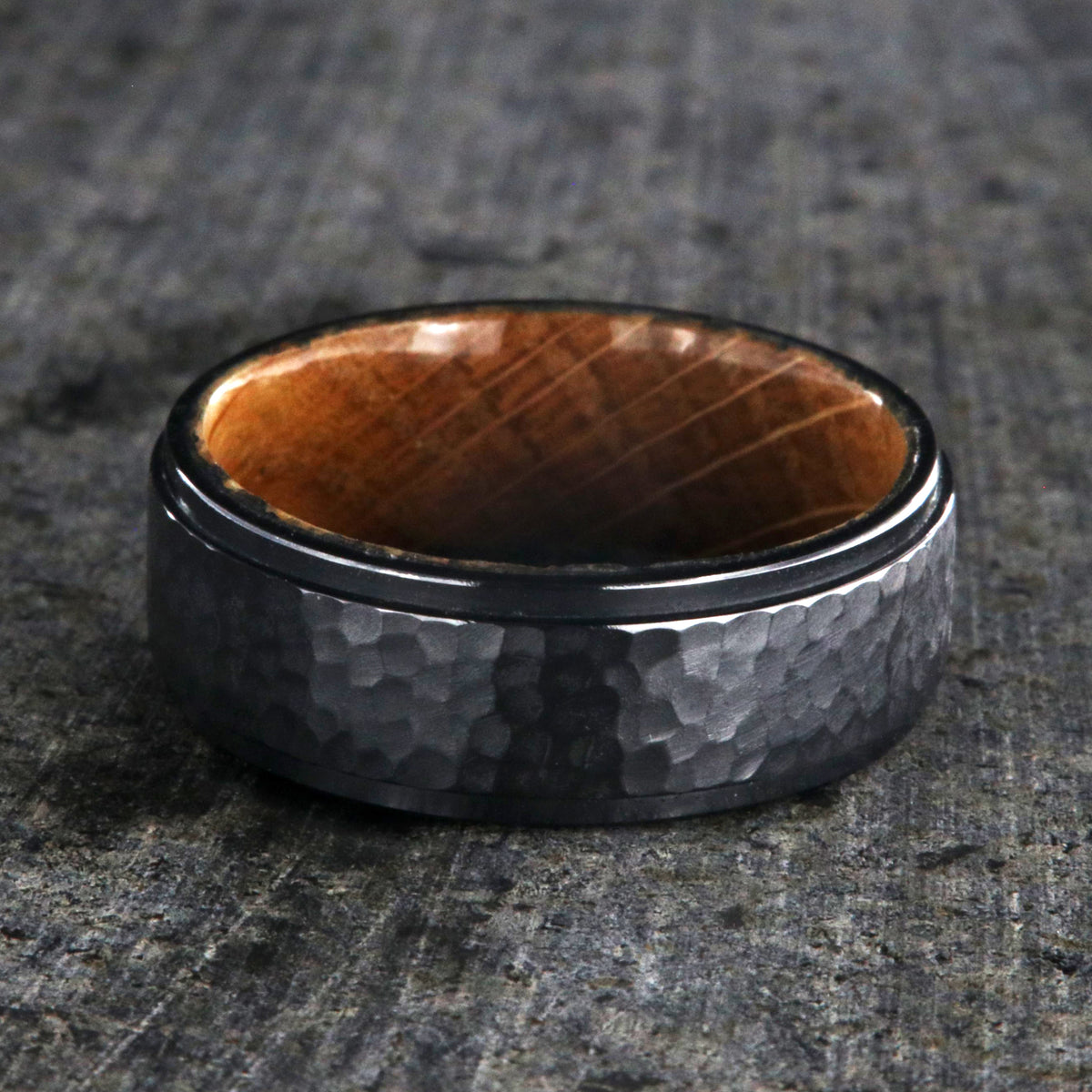 8mm wide black titanium wedding band with a raised center and hammered finish with a whiskey barrel sleeve