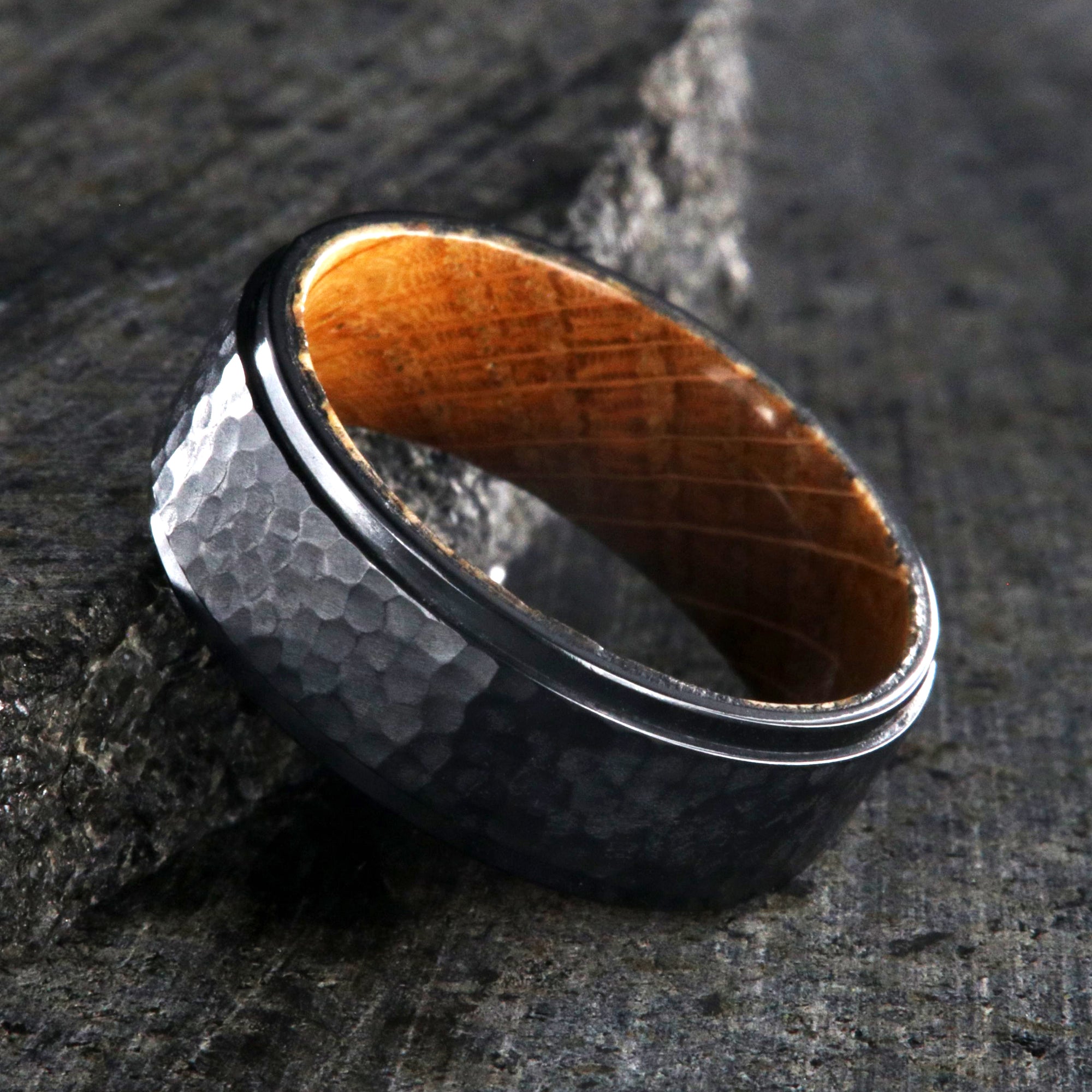 8mm wide black titanium wedding band with a raised center and hammered finish with a whiskey barrel sleeve