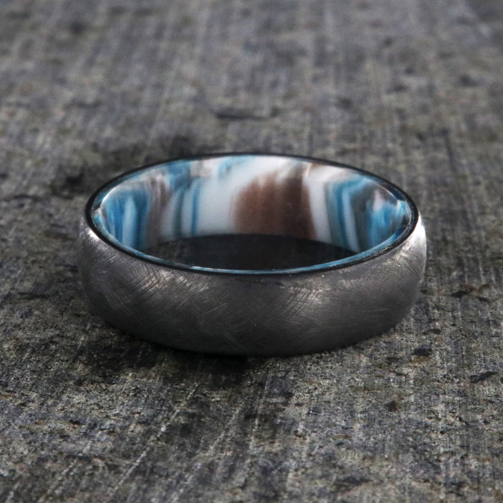 6mm wide black zirconium wedding band with a distressed finish and a blue, white, and brown DiamondCast sleeve