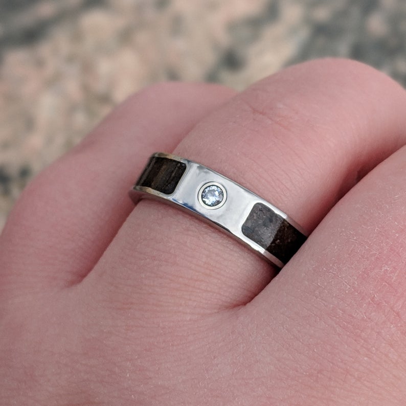 6mm wide titanium ring with a dinosaur inlay and bezel set ruby on hand