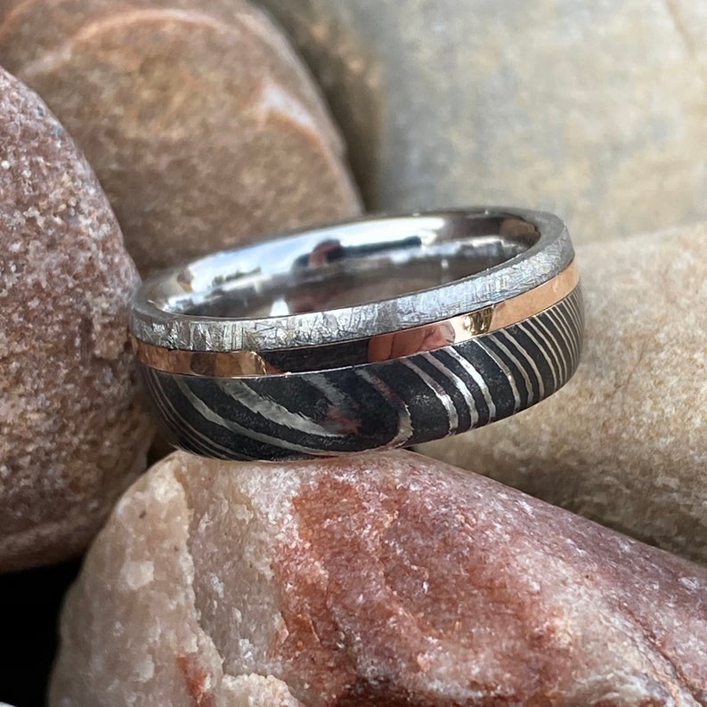6mm wide men's wedding band with a wide edge of black Damascus, a center rose gold inlay, and thin meteorite edge