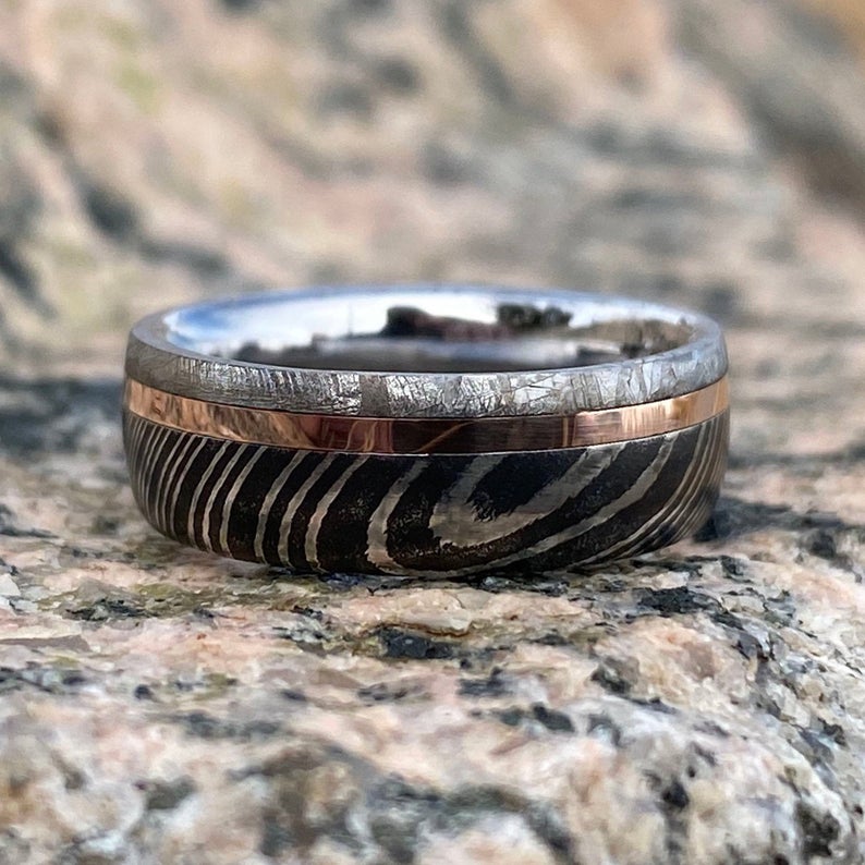 6mm wide men&#39;s wedding band with a wide edge of black Damascus, a center rose gold inlay, and thin meteorite edge