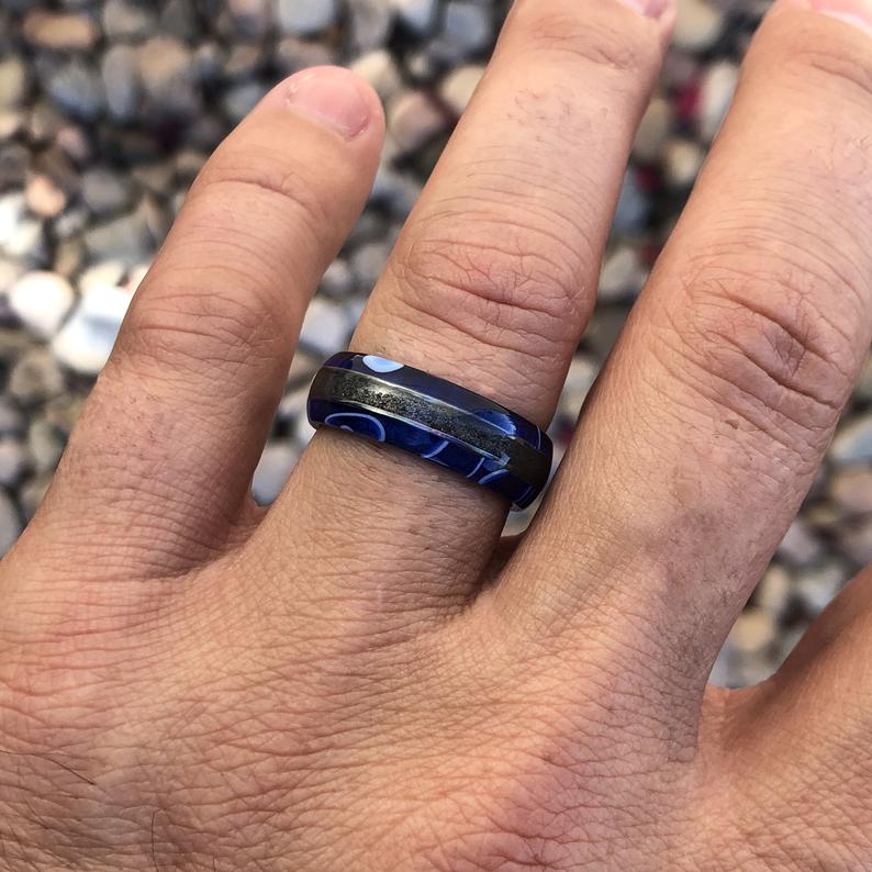 7mm wide swirled blue acrylic ring with black stardust center inlay and black zirconium sleeve on man&#39;s hand