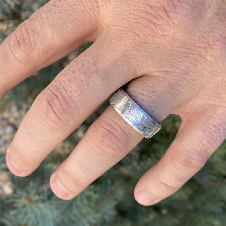 8mm wide Gibeon meteorite ring with black titanium sleeve and rounded profile on man&#39;s hand