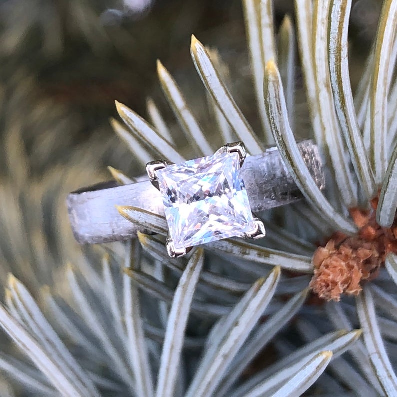 4mm wide women&#39;s meteorite engagement ring with a princess cut moissanite stone