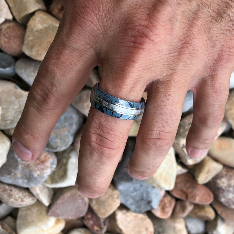 8mm wide cobalt ring for men with Gibeon meteorite center inlay and black and blue cobaltium mokume edges on man&#39;s hand