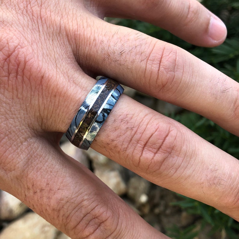 9mm wide ring for men with blue and black cobaltium mokume edges and a dinosaur bone inlay on hand
