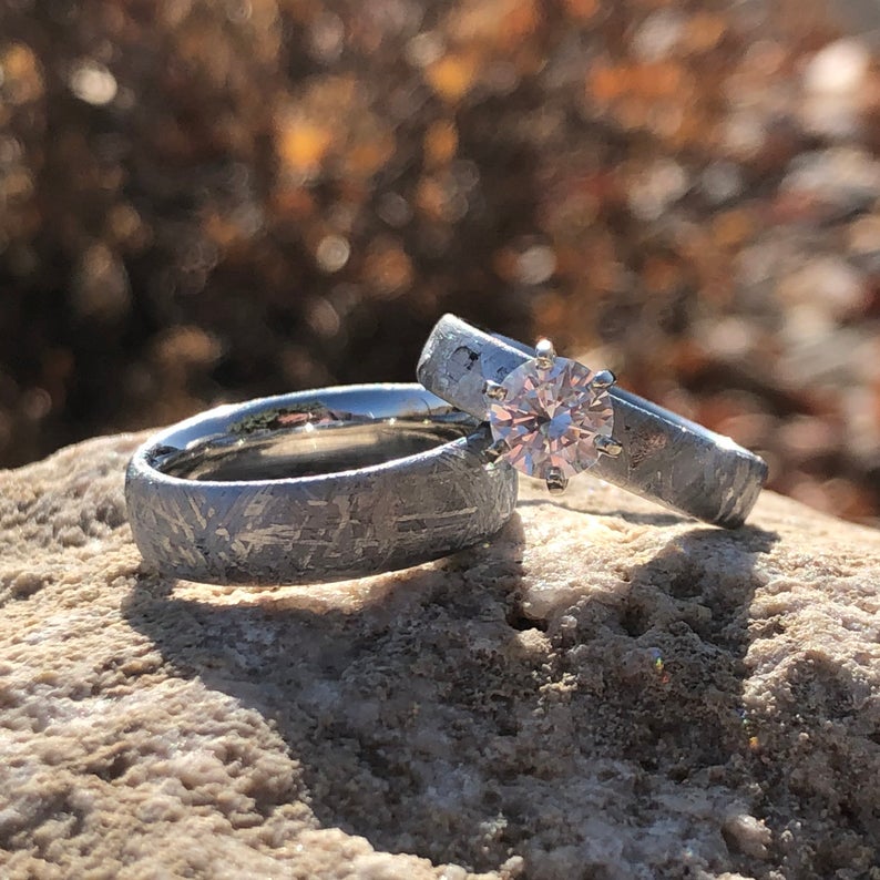 6mm wide men's meteorite wedding band and 4mm wide women's meteorite engagement ring with 1 carat round cubic zirconium