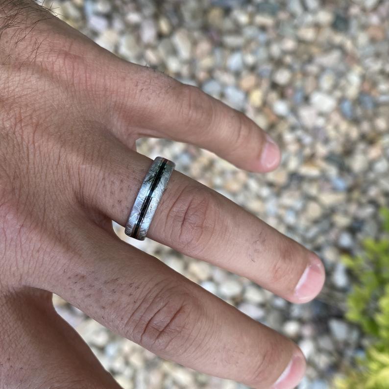 5mm wide meteorite wedding band with a black stardust center inlay  on man&#39;s hand