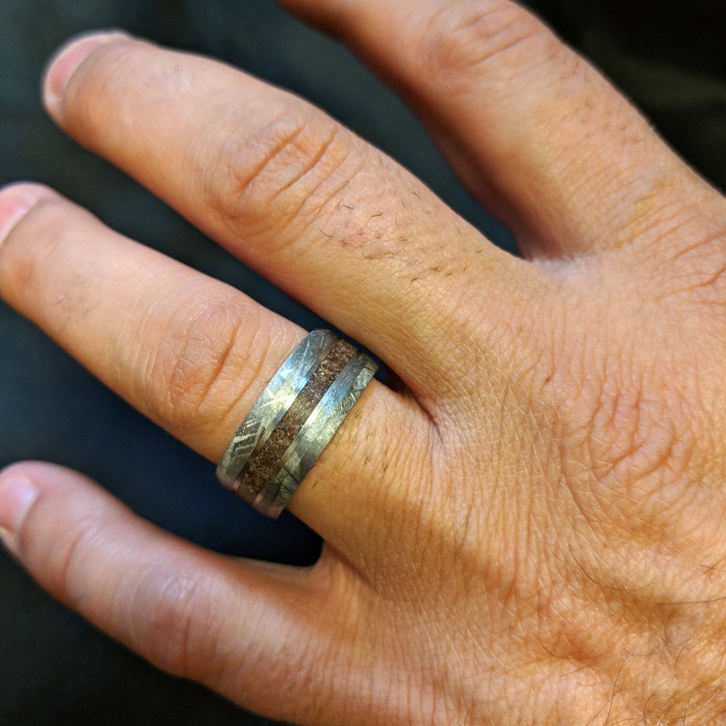 9mm wide cobalt wedding band with meteorite edges and beveled edges with Tyrannosaurus rex bone inlay on a man&#39;s hand