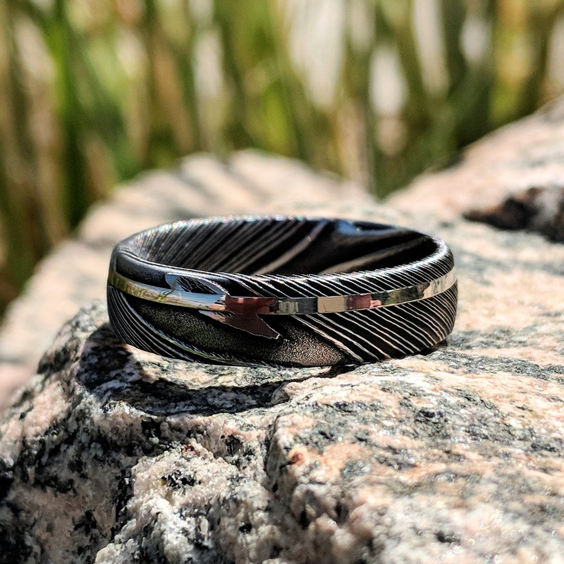 6mm wide black Damascus steel ring with an off-center white gold inlay