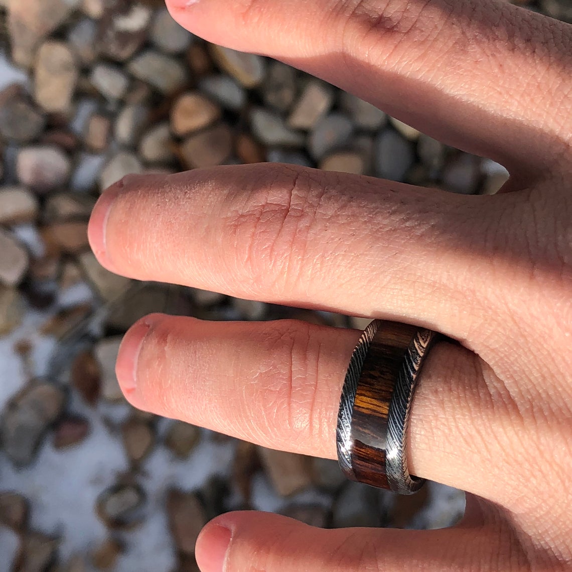 10mm wide Damascus steel ring with a 5mm wide Arizona ironwood inlay on a man&#39;s hand