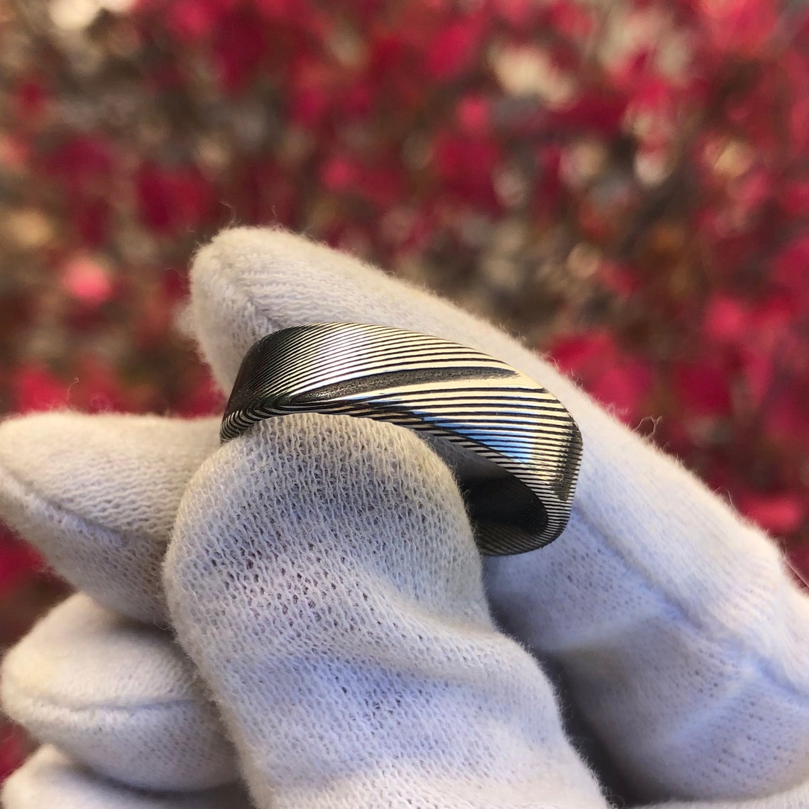6mm wide Damascus steel wedding band with a flat profile held by a gloved hand