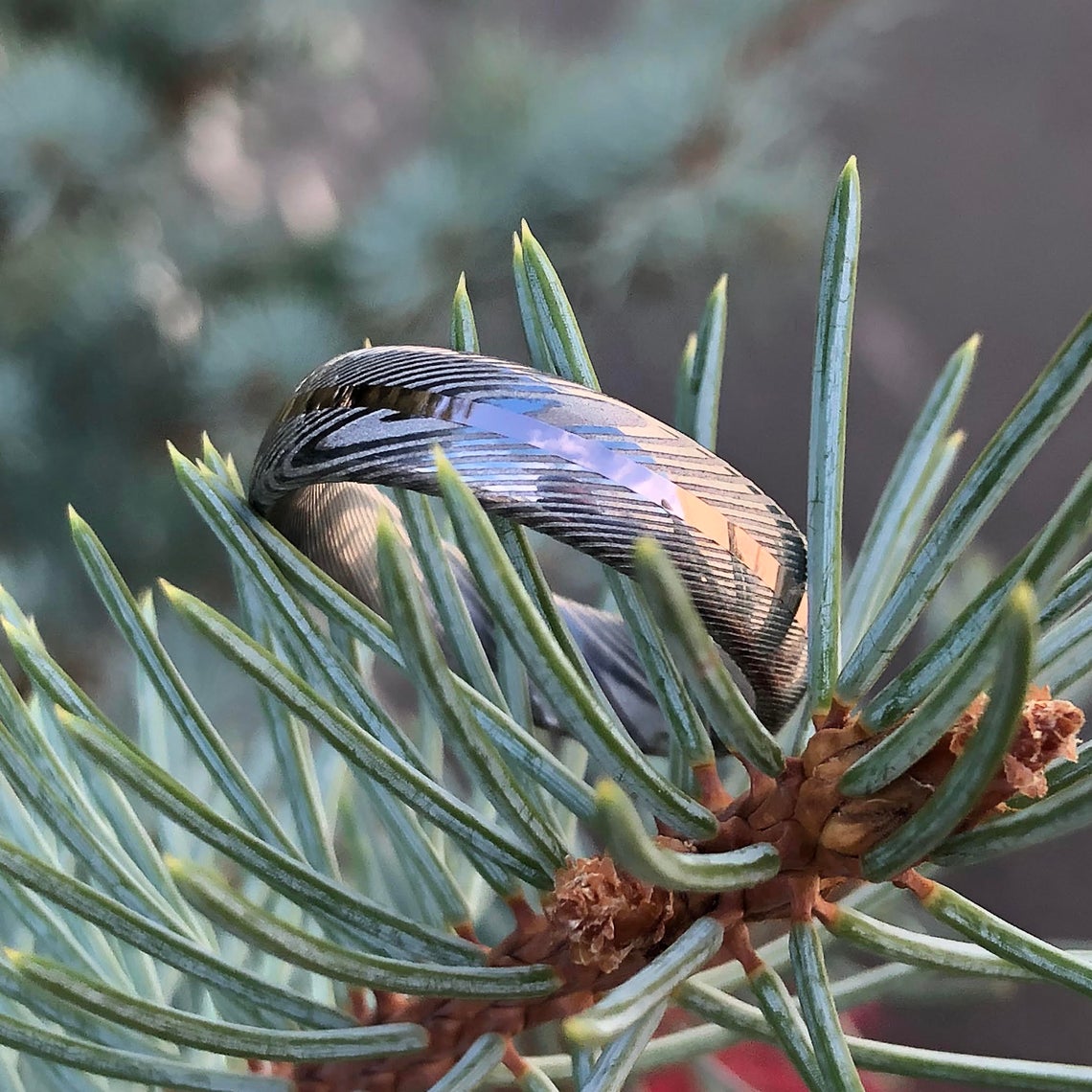 6mm wide Damascus steel wedding band with a centered rose gold inlay
