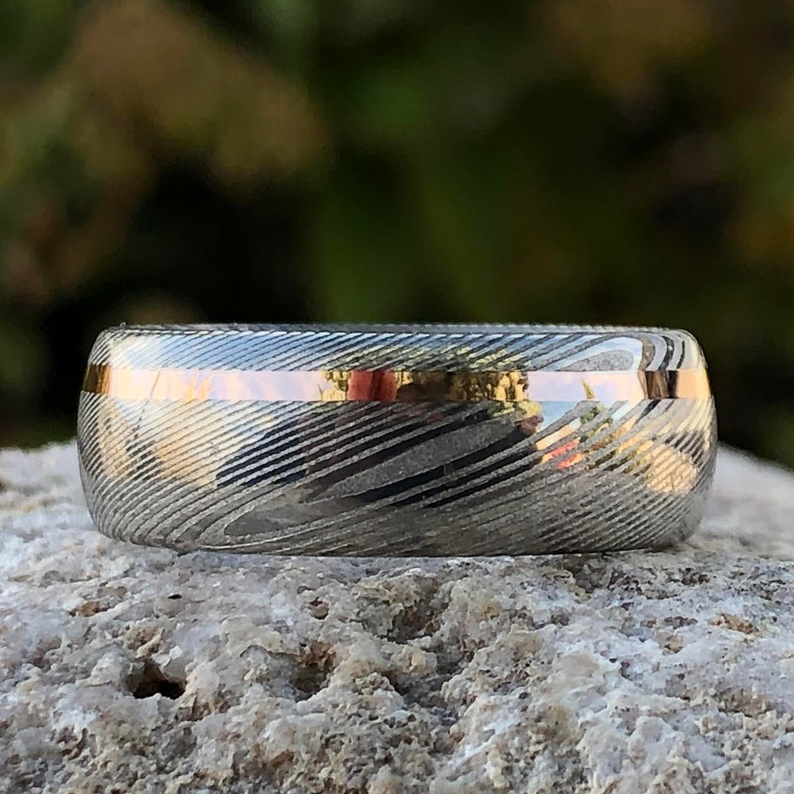 8mm wide white Damascus steel ring with an off-centered rose gold inlay and rounded profile