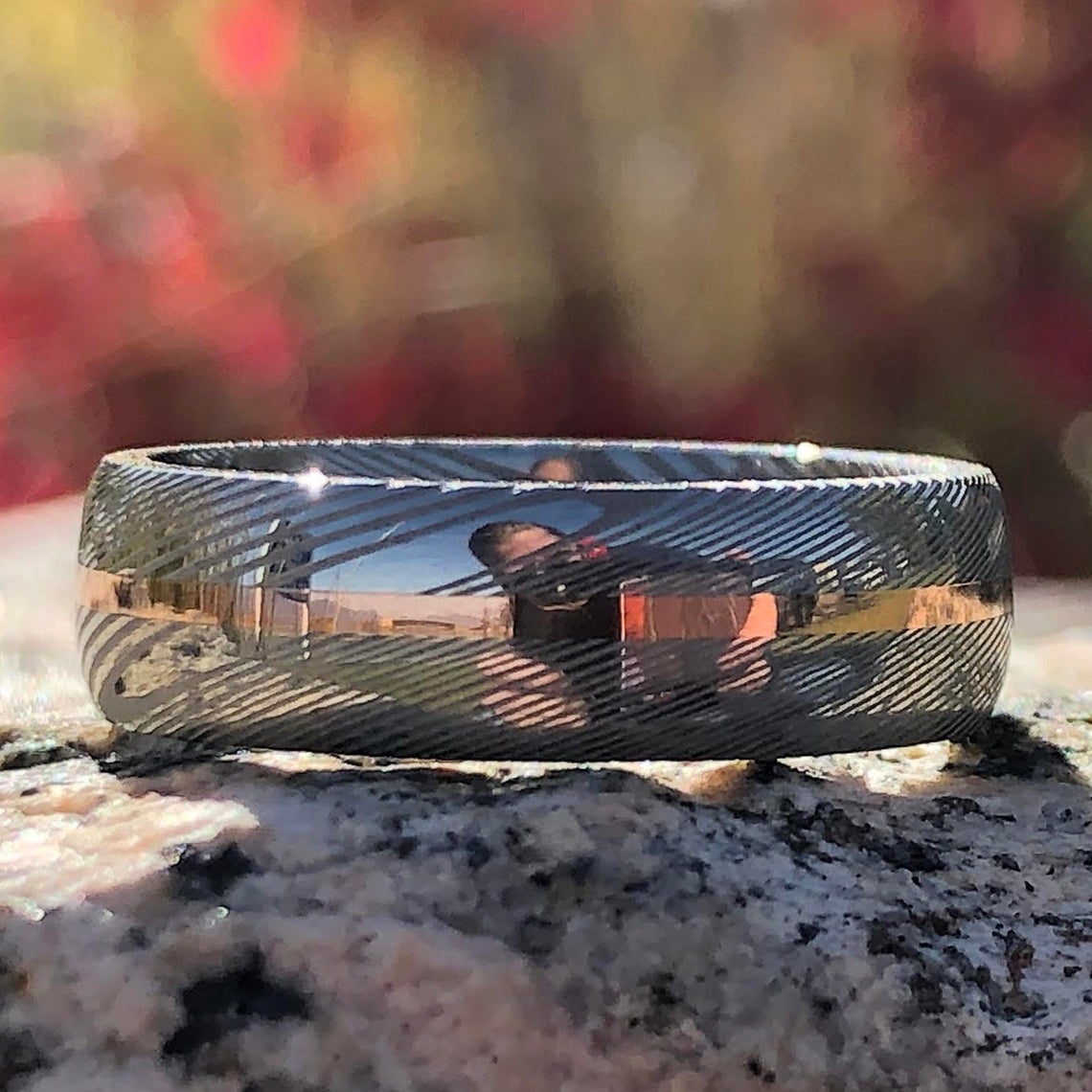 7mm wide white Damascus steel ring with a centered rose gold inlay