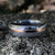 7mm wide white Damascus steel ring with a centered rose gold inlay