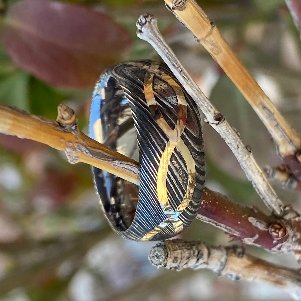 8mm wide Black Damascus steel ring with a 14k yellow gold infinity inlay