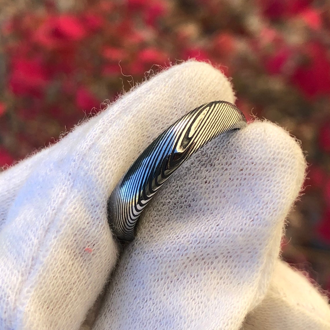 5mm wide Damascus steel wedding band held by a white glove