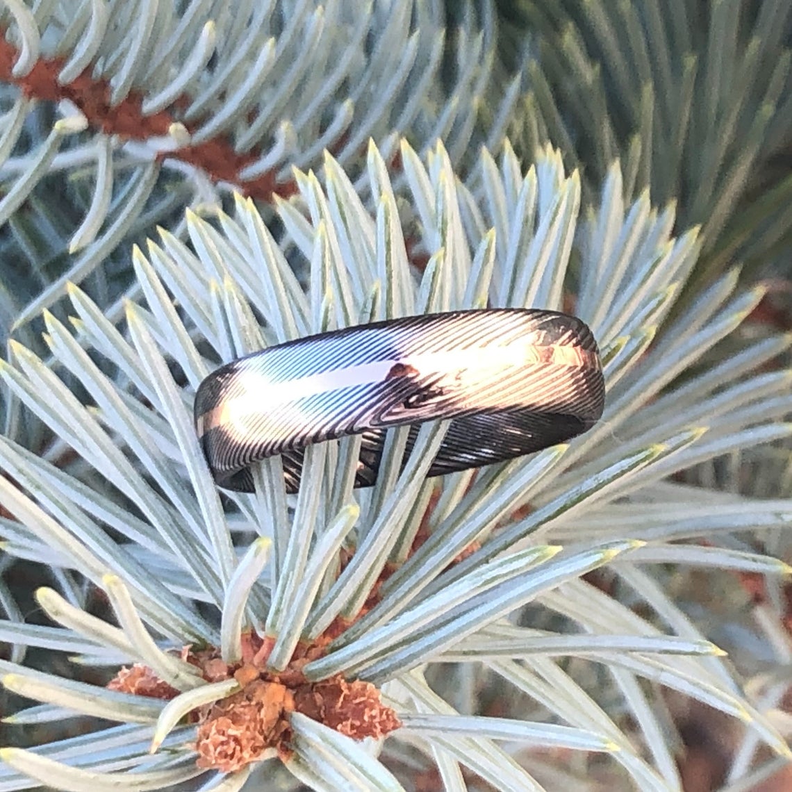 6mm wide Damascus steel ring with a centered rose gold inlay and a rounded profile