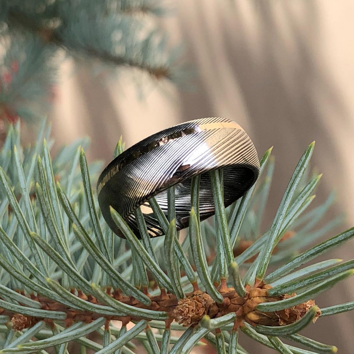 8mm wide Damascus steel ring with an off-centered  rose gold inlay