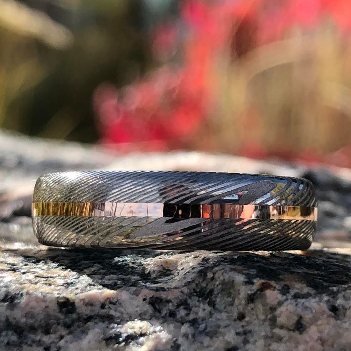 6mm wide Damascus steel wedding band with a centered rose gold inlay