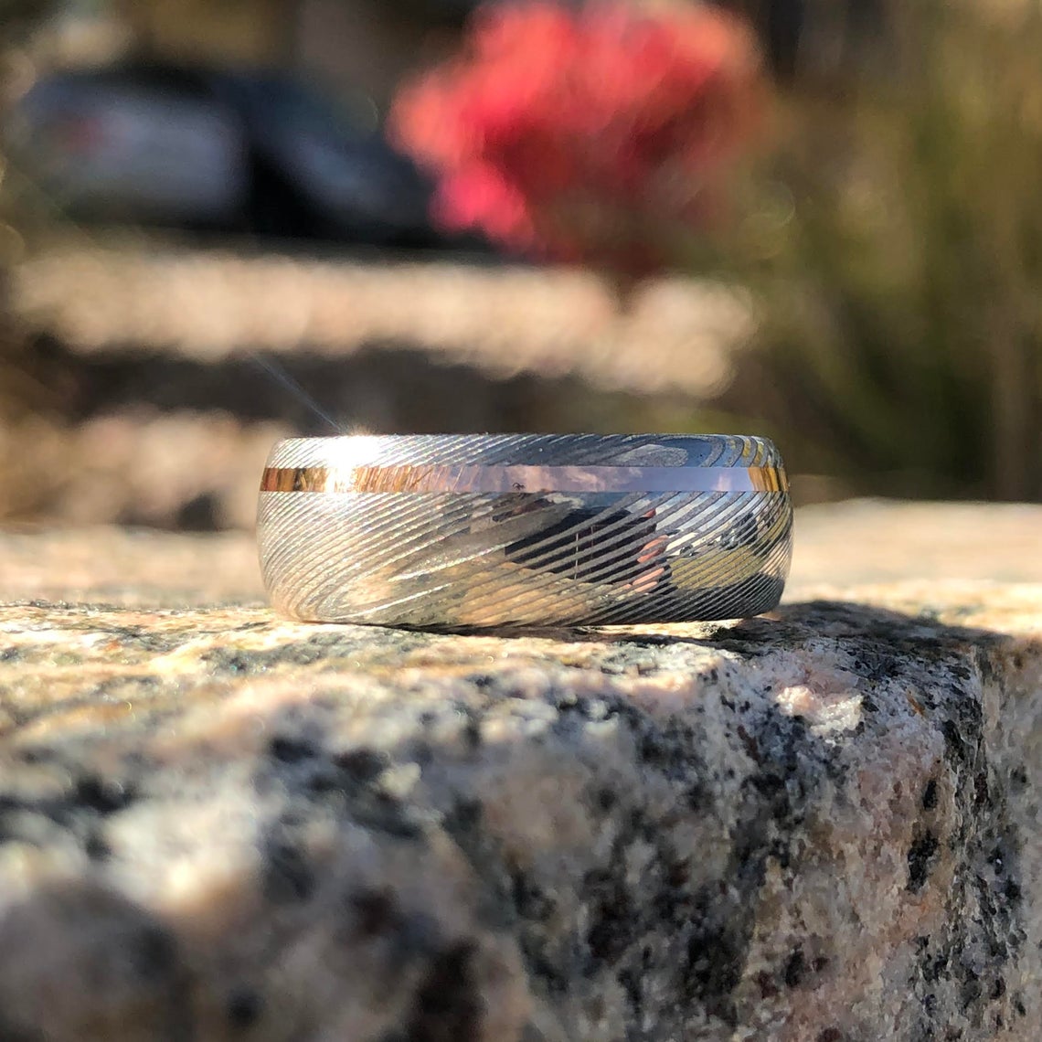 8mm wide white Damascus steel ring with an off-centered rose gold inlay and rounded profile