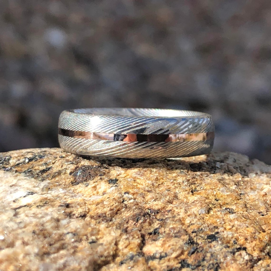 6mm wide Damascus steel wedding band with a centered rose gold inlay
