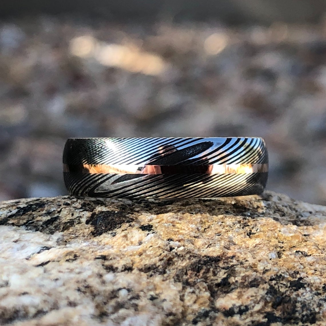 7mm wide Damascus steel ring with a centered rose gold inlay
