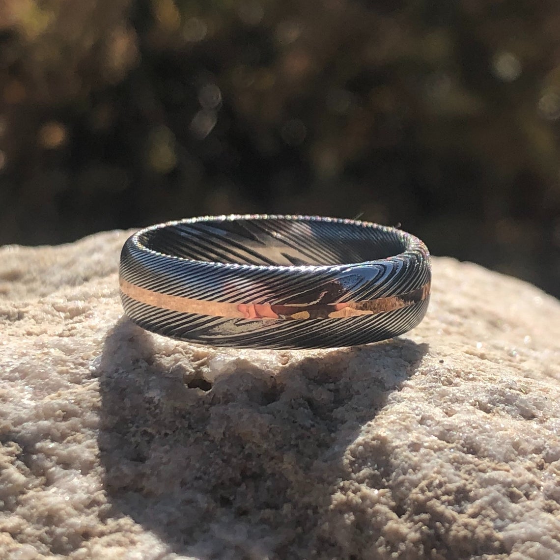 6mm wide Damascus steel ring with a centered rose gold inlay and a rounded profile