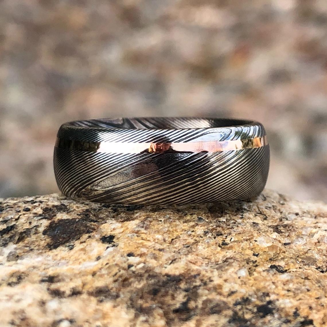 8mm wide Damascus steel ring with an off-centered  rose gold inlay