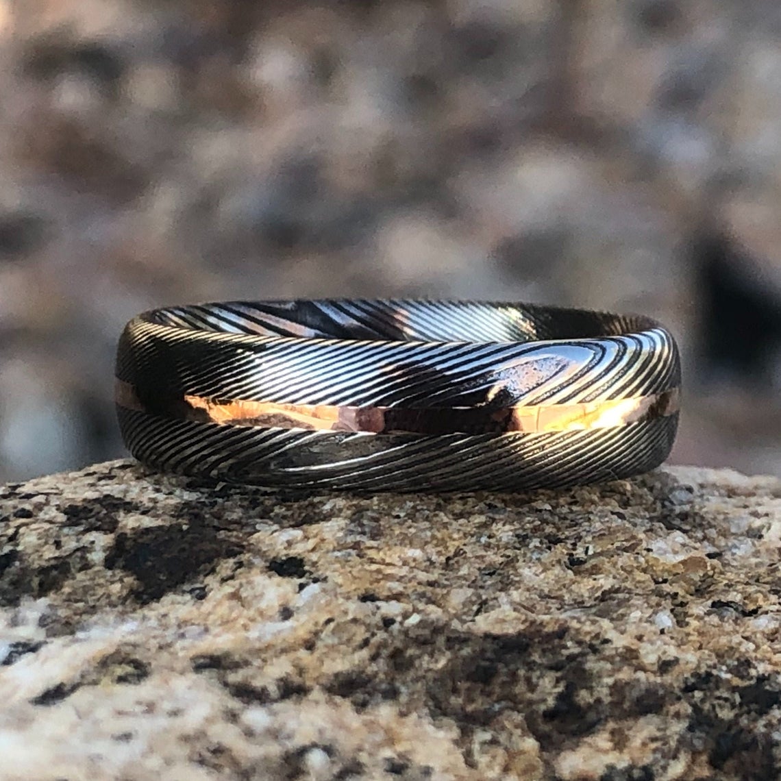 6mm wide Damascus steel ring with a centered rose gold inlay and a rounded profile