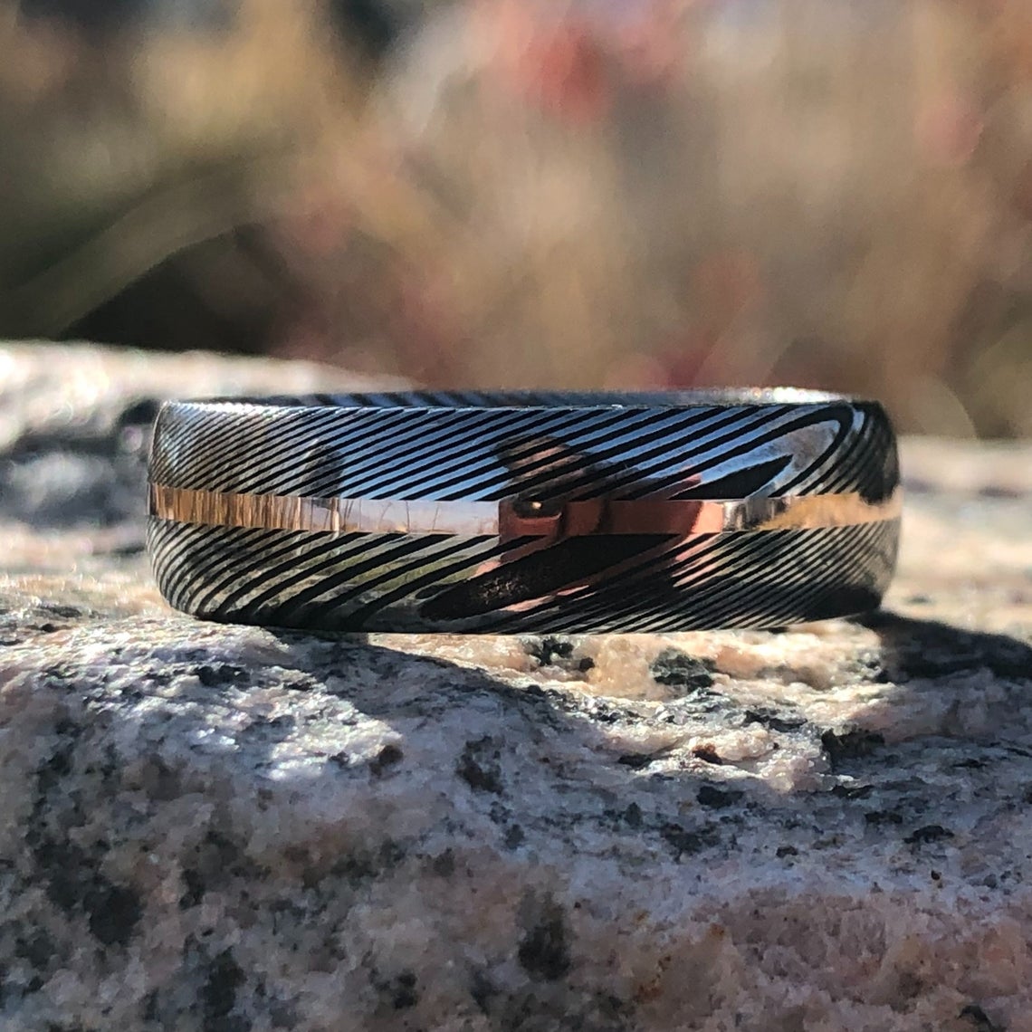 7mm wide Damascus steel ring with a centered rose gold inlay