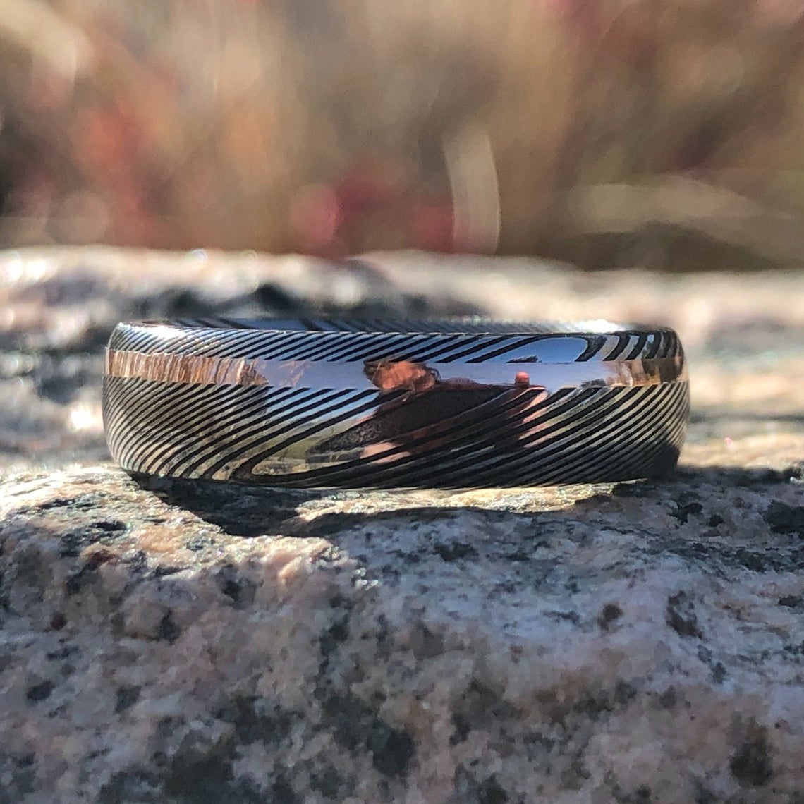 6mm wide Damascus steel ring with an off-centered rose gold inlay
